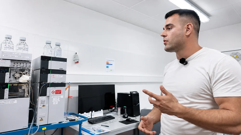 Speaker beside analytical equipment in the Janoshik laboratory