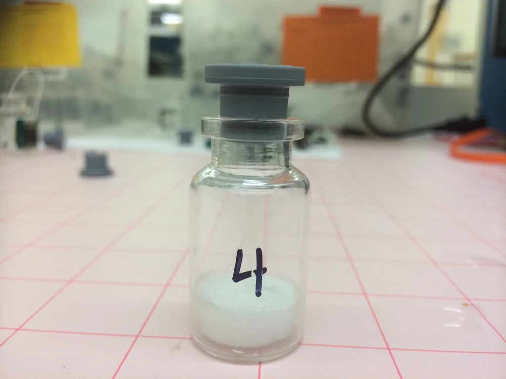 A glass vial holding a white freeze-dried peptide cake at the bottom.